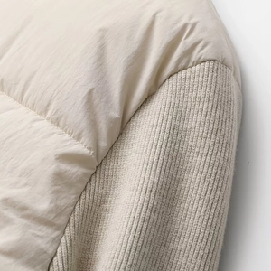 Detail shot of the contrast knit sleeve and windproof fabric on a beige quilted jacket