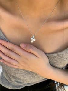 Close-up of a three-pearl flower cluster necklace on model with shimmering zircon center