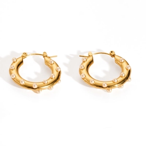 Detailed view of golden hoop earrings with embedded white pearls and polished finish