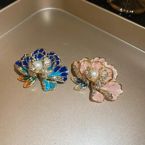 Detailed close-up of floral brooches with enamel petals, crystals and pearls in a gold tray