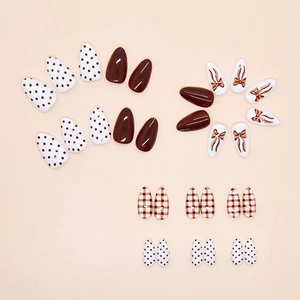 Press-on nail set featuring caramel plaid, polka dots, and bow-tie almond shape tips