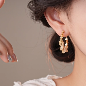 Close-up of a model wearing gold braided knot earrings with sparkling zircon inlay