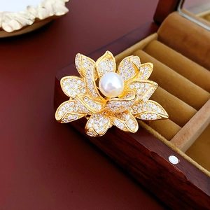 Macro view of gold-plated flower brooch with sparkling cubic zirconia and a large pearl