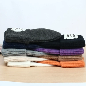 Stack of colorful ribbed knit beanies with patch labels in multiple autumn shades