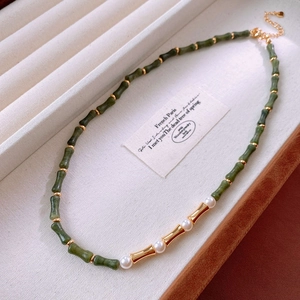 Détail du collier avec perles de jade en forme de bambou et perles blanches sur velours