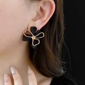 Close-up of a model wearing black double-layer hollow flower earrings with gold edges