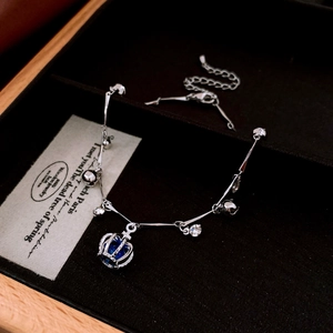 Détail du bracelet couronne avec zircon bleu et clochettes dans son écrin noir
