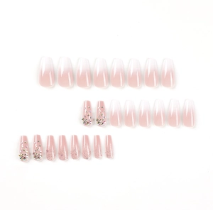 Pink and white ombre press-on nails with glitter and rhinestones in coffin shape