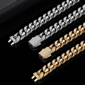 Silver and gold stainless steel Cuban link chains with iced out diamond claps on black surface
