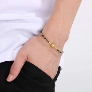Macro view of 3mm black and gold woven bracelet with detailed lucky cloud metal buckle