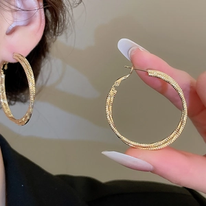 Macro shot of large golden hoop earrings with shimmering textured diamond-cut finish
