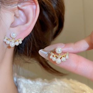 Detail of fan-shaped gold earrings with white pearls and sparkling cubic zirconia