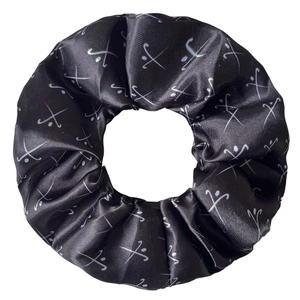 Détail d'un chouchou en satin noir avec motifs argentés de bâtons de hockey et balles