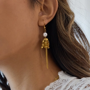 Close-up of vintage 18K gold earrings with white pearl and geometric tassel on model