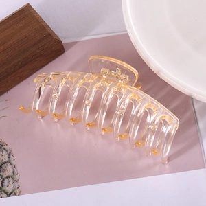 Close-up of a large amber-toned transparent plastic hair claw clip with a hollow bone structure