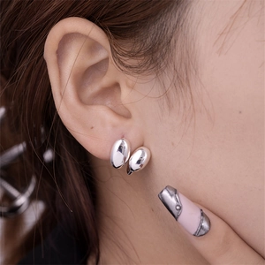Close-up of silver crescent U-shaped hollow earrings with a polished mirror finish