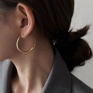 Close-up of model wearing large minimalist gold hoop earrings with a sleek modern design