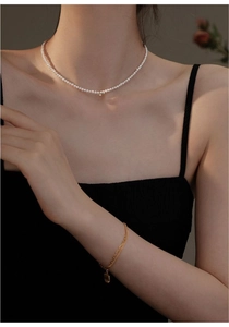 Detail of baby freshwater pearl choker necklace with gold bead and minimalist chain bracelet