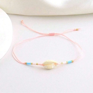 Detailed close-up of pink woven cord with ivory shell pendant and golden beads