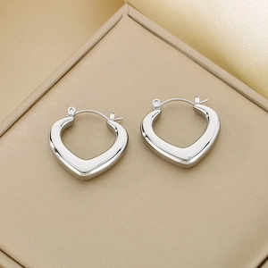 Detailed view of silver heart-shaped polished earrings on a luxury jewelry display stand