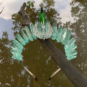 Close-up of raw blue-green crystals and silver crescent moon detail on a forest branch