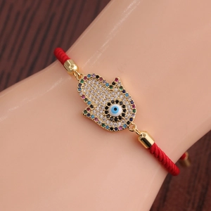 Vue détaillée du bracelet en corde rouge tressée avec main de Hamsa et œil bleu