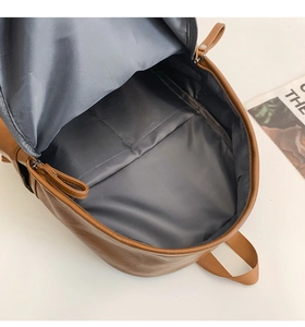 Interior view of brown leather backpack showing spacious gray lining and compartment