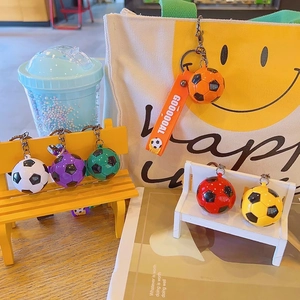 Colorful soccer ball keychains with GOOOOOAL silicone wristbands on a mini wooden bench