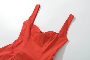 Détail d'une robe rouge moulante avec décolleté en cœur structuré et larges bretelles