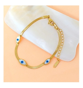 Detail of gold stainless steel snake chain bracelet with blue evil eye charms and lobster clasp