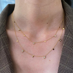 Detailed view of layered gold necklace with geometric zircon pendants on a model