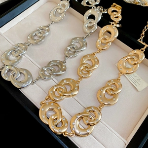 Close-up of interlocking diamond-encrusted geometric gold and silver chain belts in a gift box