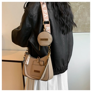 Detail of beige shoulder bag with detachable coin purse, chain, and wide printed strap