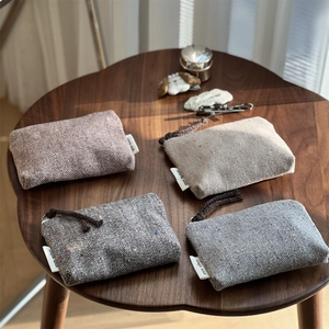 Herringbone tweed mini coin pouches in four colors with colorful speckles on wood table