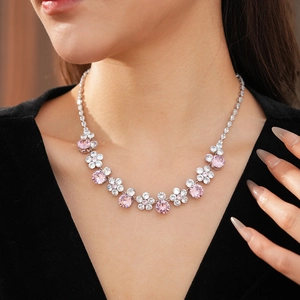 Close-up of elegant flower necklace with pink and white cubic zirconia on a black dress