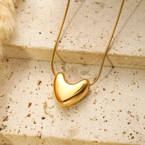 Detailed close-up of golden heart pendant on textured beige stone background