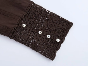 Detail of dark brown sleeve with white buttons and intricate lace embroidery pattern