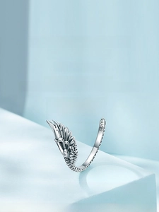 Macro shot of S925 sterling silver wing ring detailing delicate feather textures on light blue background