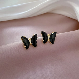 Macro shot of butterfly stud earrings with black wings, gold edges and tiny white zircons