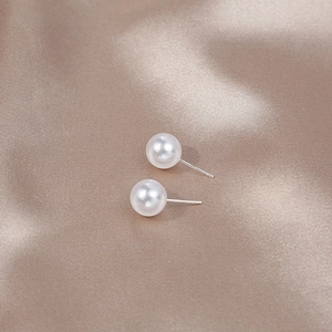 Close-up of elegant white pearl stud earrings on satin with S925 silver hallmark