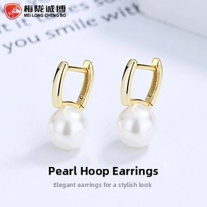 Close-up of elegant gold plated water bucket pearl earrings on a light blue background