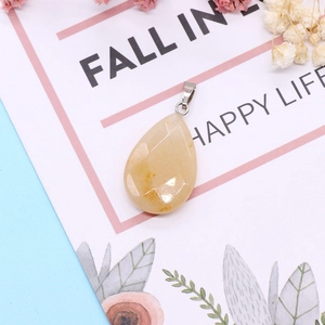 Macro shot of faceted yellow teardrop gemstone pendant with silver clasp on floral card
