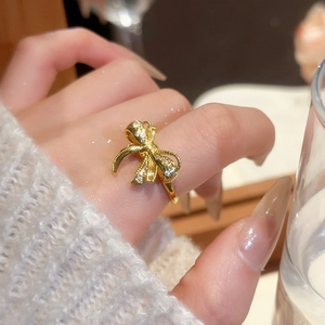 Macro detail of 18k gold plated bow ring with sparkling zircons and textured finish