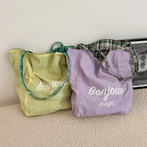 Close-up of lightweight canvas tote bag with Bonjour magic print and plaid straps