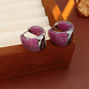 Macro detail of rose red zircon C-hoop earrings on a brown velvet jewelry gift box