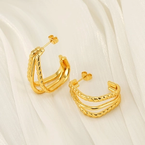 Three-layer 18K gold C-shaped twisted rope earrings on a soft white silk background