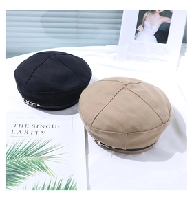 Detail of vintage beret hats in black and khaki with trendy star metal chain accents