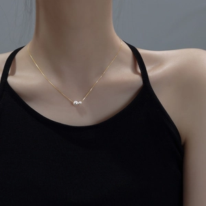 Close-up of elegant gold chain necklace with double pearls worn by a model