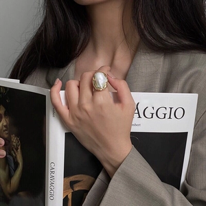 Artistic close-up of a gold irregular pearl ring worn while holding a Caravaggio book