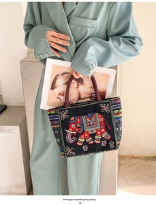 Detailed embroidery of colorful elephant and floral patterns on black canvas handbag